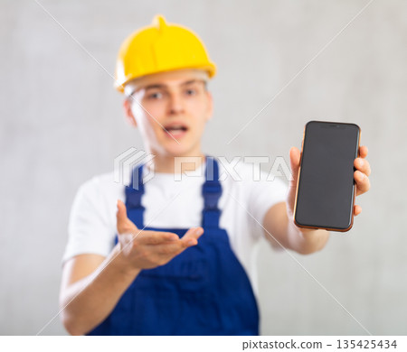 Surprised young guy posing in uniform with phone in his hand Surprised young guy posing in uniform with phone in his hand 135425434