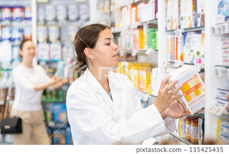 Woman seller puts medical cosmetics and other body care products on shelves Woman seller puts medical cosmetics and other body care products on shelves 135425435
