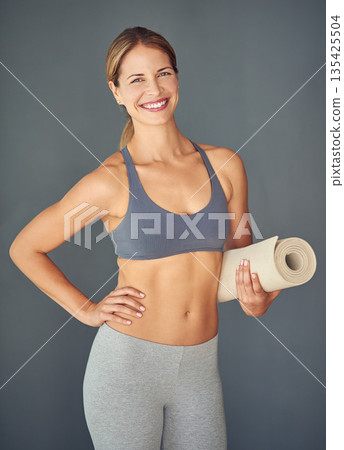 Woman, fitness and portrait smile for yoga, zen workout or healthy exercise against a grey studio background. Happy female person or yogi smiling with mat for spiritual wellness and mental health Woman, fitness and portrait smile for yoga, zen workout or healthy exercise against a grey studio background. Happy female person or yogi smiling with mat for spiritual wellness and mental health 135425504