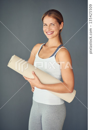 Happy woman, portrait smile and yoga mat for exercise, healthy wellness or workout against a grey studio background. Excited female person or yogi smiling for mindfulness, zen fitness or body health 135425509