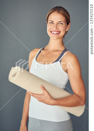 Happy woman, yoga and portrait smile with mat for exercise, healthy wellness or workout against a grey studio background. Excited female person or yogi smiling for mindfulness, fitness or body health Happy woman, yoga and portrait smile with mat for exercise, healthy wellness or workout against a grey studio background. Excited female person or yogi smiling for mindfulness, fitness or body health 135425510