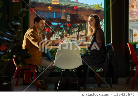 Man and woman sitting at table in cafe with drinks 135425675