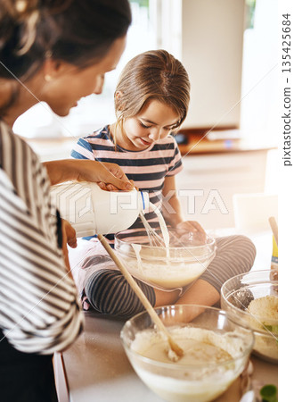 Mother, milk or girl baking in kitchen as a happy family with a kid learning cookies or cake recipe at home. Smile, cooking or mother baker helping or teaching daughter to bake for child development 135425684