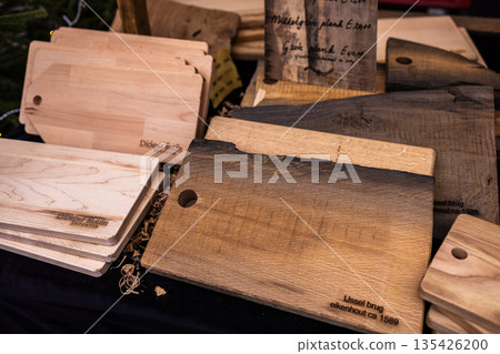 Wooden cutting boards with varied grains and finishes displayed at market, engraved historical references. Wooden cutting boards with varied grains and finishes displayed at market, engraved historical references. 135426200