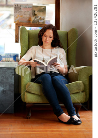Education, woman reading a book and sitting on a couch at a local bookstore. Research or learning, studying or research and female person read a textbook or notebook on a sofa for knowledge. Education, woman reading a book and sitting on a couch at a local bookstore. Research or learning, studying or research and female person read a textbook or notebook on a sofa for knowledge. 135426281