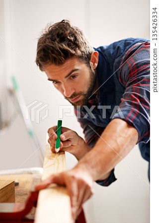 Man, wood and pencil for measure for construction, home development and building renovation. Carpenter, maintenance employee and male repairman worker on a contractor job of builder working in house 135426334