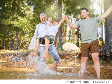 Hiking, grandfather and dad swinging a boy with a water splash in the forest while on a camping trip together. Children, adventure and a family walking over a river while in the woods or wilderness Hiking, grandfather and dad swinging a boy with a water splash in the forest while on a camping trip together. Children, adventure and a family walking over a river while in the woods or wilderness 135426374