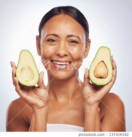 Avocado, portrait and beauty of woman in studio, white background and face glow. Happy mature model, natural skincare and fruits for sustainable cosmetics, vegan dermatology and facial benefits 135426382