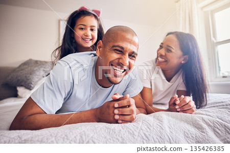 Mother, father and child laughing on a bed in a family home while happy and playing for quality time. Man, woman or parents and girl kid together in the bedroom for morning bonding with love and care 135426385
