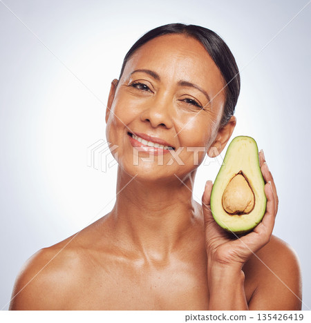 Face, skincare and senior woman with avocado in studio isolated on a white background. Portrait, natural fruit and happy model with food for organic nutrition, healthy diet and omega 3 for anti aging 135426419