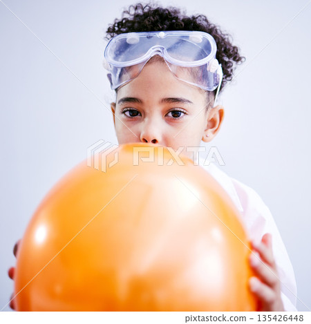 Portrait, science and a kid blowing a balloon in studio on a gray background for a childhood experiment. Children, education and laboratory with a female child wearing goggles while learning 135426448