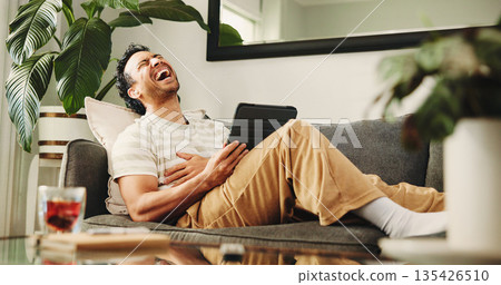 Man, tablet and laugh on sofa, relax and streaming service for funny movies in living room at home. Person, tech and happy with app, video and comedy film on web, couch or subscription at apartment 135426510