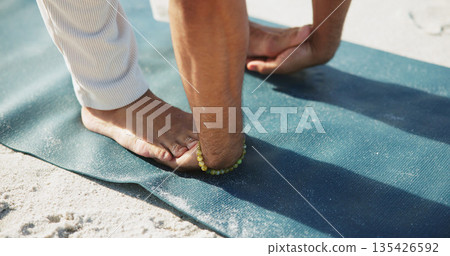 Yoga, person and hands with feet on beach for spine stretching, holistic practice and flexibility. Fitness, yogi and padahastasana pose on sand for spiritual wellness, core strength and stress relief 135426592