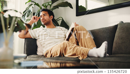 Man, journal and thinking on sofa in house, daily reflection or idea notes to relax for creativity. Person, notebook for plan or inspiration for agenda in diary, to do list or goal setting in home Man, journal and thinking on sofa in house, daily reflection or idea notes to relax for creativity. Person, notebook for plan or inspiration for agenda in diary, to do list or goal setting in home 135426720