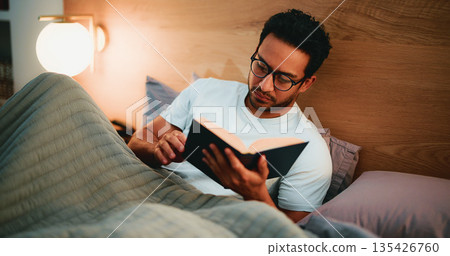 Reading book, night and man in bed, glasses and entertainment with fiction story. Evening, eyewear and person with novel, house and hobby with cozy activity, literature and comfortable with poetry 135426760