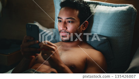 Night, man and typing in bed with phone for text message reply, social media and check dating site. Late, person and browsing with tech in apartment for online conversation, internet and mobile app. Night, man and typing in bed with phone for text message reply, social media and check dating site. Late, person and browsing with tech in apartment for online conversation, internet and mobile app. 135426807