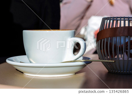 White coffee cup on saucer at cafe table with candle holder and copy space White coffee cup on saucer at cafe table with candle holder and copy space 135426865
