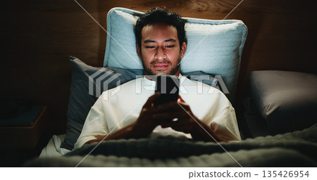 Night, man and scroll in bed with phone for text message reply, social media and watching viral video. Late, person and browse with tech in apartment for online conversation, internet and mobile app. 135426954