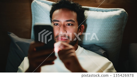 Night, man and scroll in bedroom with phone for text message reply, social media and watching video. Late, person and browse with tech in apartment for online conversation, internet and mobile app. 135426978