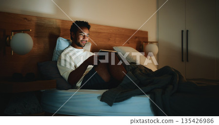 Tablet, calm and man in bed in home at night for watching movie, series or film for entertainment. Technology, app and male person streaming show online on website in bedroom in evening at house. Tablet, calm and man in bed in home at night for watching movie, series or film for entertainment. Technology, app and male person streaming show online on website in bedroom in evening at house. 135426986