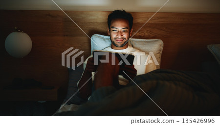 Tablet, smile and man in bed in home at night for watching movie, series or film for entertainment. Technology, relax and male person streaming show online on website in bedroom in evening at house. Tablet, smile and man in bed in home at night for watching movie, series or film for entertainment. Technology, relax and male person streaming show online on website in bedroom in evening at house. 135426996