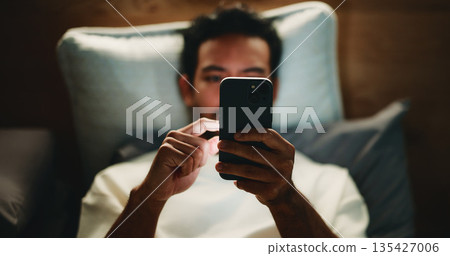 Night, man and hands in bed with phone for text message reply, social media and watching viral video. Late, person and scroll with tech in apartment for online conversation, internet and mobile app. Night, man and hands in bed with phone for text message reply, social media and watching viral video. Late, person and scroll with tech in apartment for online conversation, internet and mobile app. 135427006