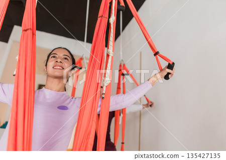 Young latin woman enjoying aerial yoga workout 135427135