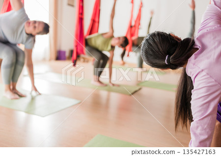 Women practicing yoga in aerial vinyasa class Women practicing yoga in aerial vinyasa class 135427163