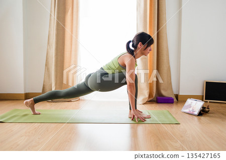 Hispanic woman practicing yoga at home online 135427165