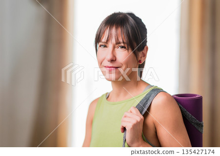 Woman carrying yoga mat ready for wellness class Woman carrying yoga mat ready for wellness class 135427174
