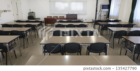 Empty classroom/conference room with neatly arranged desks and chairs Empty classroom/conference room with neatly arranged desks and chairs 135427790