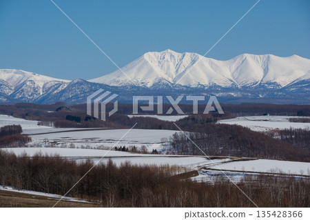 Field of remaining snow in spring and snowy mountains Tokachidake mountain range 135428366