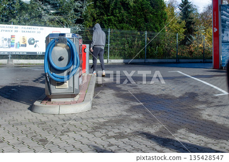 Man uses car wash station on a sunny day in a quiet location 135428547