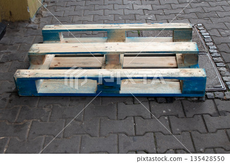 Wooden pallet rests on a cobblestone street near a building in an urban area 135428550