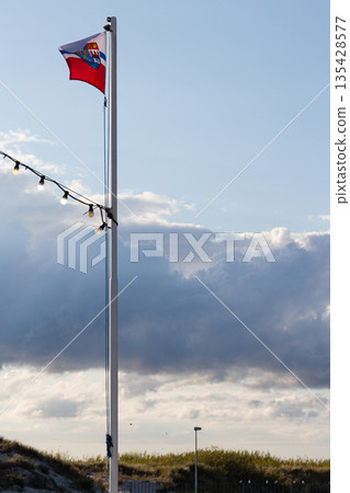 Flag flying against a dramatic sky at a coastal location with soft evening light 135428577
