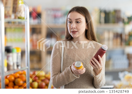 Young woman chooses red and yellow smoothies Young woman chooses red and yellow smoothies 135428749