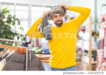 Young man choosing winter hat in clothing store 135428779