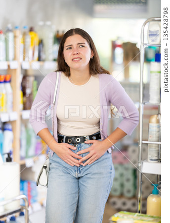 Woman with stomach pain in household chemicals store Woman with stomach pain in household chemicals store 135428798