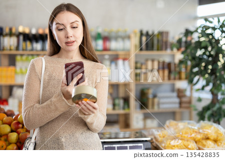 Young woman scanning barcode on canned food in grocery store Young woman scanning barcode on canned food in grocery store 135428835