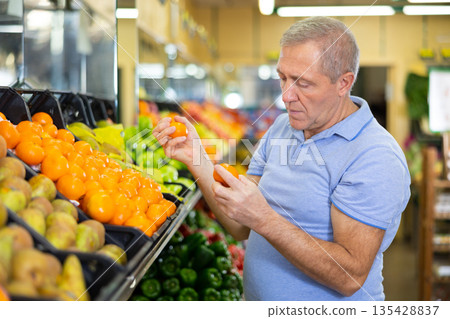 man buys tangerines in supermarket man buys tangerines in supermarket 135428837