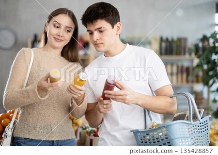 Couple young man and woman chooses red and yellow smoothies 135428857