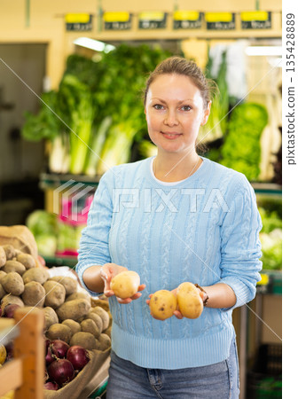 housewife in vegetable shop chooses high-quality potato 135428889