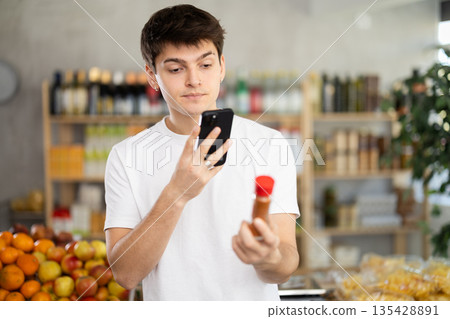 In shop guy scans QR code and take reading chopped red ground pepper using phone camera 135428891