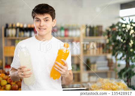 Male shopper chooses bottle of sweet water while shopping at supermarket 135428917