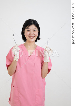 身穿手術服、手持牙科設備的微笑女子 135429348