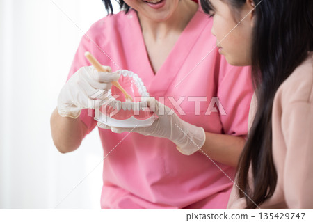 特寫鏡頭：一位牙齒保健員正在使用模型示範如何刷牙。 135429747