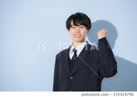 A high school boy's upper body is looking at the camera with a fist pump against a light blue background. This image is of him studying for exams and pursuing his future. A high school boy's upper body is looking at the camera with a fist pump against a light blue background. This image is of him studying for exams and pursuing his future. 135429796