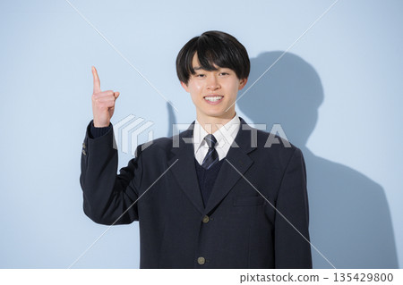 A high school boy's upper body is pointing at the camera against a light blue background. Recommended for studying for exams, career paths, etc. 135429800