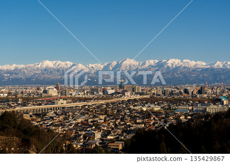 View of the Toyama cityscape and the Tateyama mountain range Abenrot from the observation deck at Kurehayama Park in Toyama City in the evening View of the Toyama cityscape and the Tateyama mountain range Abenrot from the observation deck at Kurehayama Park in Toyama City in the evening 135429867