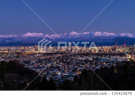 View of the Toyama cityscape and the Tateyama mountain range Abenrot from the observation deck at Kurehayama Park in Toyama City in the evening View of the Toyama cityscape and the Tateyama mountain range Abenrot from the observation deck at Kurehayama Park in Toyama City in the evening 135429879